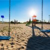 Altalene e scivolo in un parco giochi sabbioso.