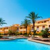 Resort con piscina e palme sotto un cielo azzurro.