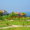 Giardino con viali e piante, vista di edifici sullo sfondo vicino al mare.