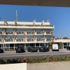 Facciata di un hotel con balconi fioriti e parcheggio.