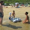 Famiglia gioca in spiaggia con gonfiabile.