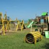 Area giochi all'aperto con attrezzature in legno giallo.