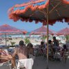 Persone sedute sotto ombrelloni colorati in spiaggia.