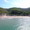 Veduta aerea di una spiaggia e colline verdi.