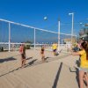 Persone che giocano a beach volley sulla sabbia.