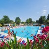 Piscina all'aperto con bagnanti e ombrelloni.