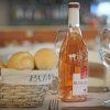 Bottiglia di vino con bicchieri e pane in cesto.