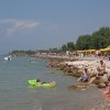 Spiaggia affollata con bagnanti e ombrelloni gialli.