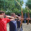Persone praticano tiro con l'arco all'aperto.