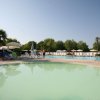 Piscina poco profonda all'aperto con lettini e ombrelloni.
