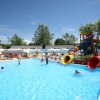 Piscina con scivoli colorati e persone che giocano.