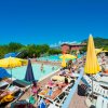 Piscina affollata con ombrelloni gialli.