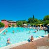 Persone che nuotano in piscina sotto il sole.