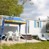 Casa mobile con veranda e sedie sotto un tendalino blu.