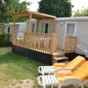 Una casa mobile con veranda e sedie a sdraio arancioni sul prato.