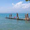 Persone sedute su un pontile al lago.