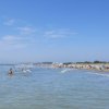 Spiaggia affollata con bagnanti e cielo sereno.