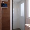 Bagno con doccia vetrata, scaffali e asciugamani.