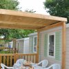 Terrazza con tavolo apparecchiato, sedie bianche e pergola in legno.