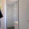 Bagno con doccia chiusa, portasciugamani blu e scaffale con prodotti.