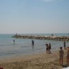 Spiaggia con bagnanti e molo di pietra.