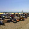 Spiaggia affollata con ombrelloni gialli e blu.