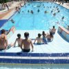 Diverse persone in una piscina affollata sotto il sole.