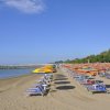 Spiaggia con file di ombrelloni arancioni e gialli.