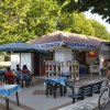 Gelateria all'aperto con tavolini ombreggiati.