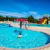 Piscina con fontana a fungo e scivolo giallo.