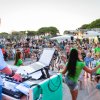 DJ alla console mentre bambini e istruttori ballano, pubblico dietro.