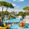 Un parco acquatico con scivoli colorati e piscine, circondato da pini.