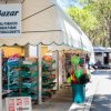 Negozio all'aperto con giornali, giochi e accessori da spiaggia sotto una tenda bianca.