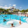 Una piscina affollata con scivoli d'acqua e persone che nuotano e si rilassano.