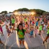 Una folla di persone balla all'aperto durante una festa, alcune indossano magliette verdi.
