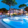 Piscina illuminata di notte con luci blu, circondata da alberi e un edificio bianco.