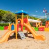 Parco giochi su sabbia con strutture colorate e scivoli.