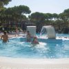 Persone che giocano in una piscina con cascate d'acqua e lettini.