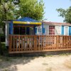 Casa mobile con veranda in legno e tenda blu e gialla.