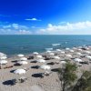 Spiaggia con ombrelloni bianchi e mare calmo.