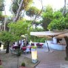 Ristorante all'aperto tra alberi e ombrelloni.