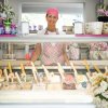 Gelataia dietro banco con vari gusti di gelato.