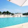 Persone in una grande piscina con ombrelloni.