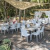 Ristorante all'aperto con tavoli e sedie bianche sotto ombrelloni.