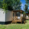 Case mobili allineate con portico in legno su prato verde.