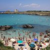Spiaggia affollata con mare azzurro.