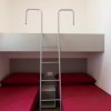 Letto a castello con scale e cuscini rossi.
