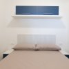 Letto matrimoniale con cuscini beige e pensile blu.