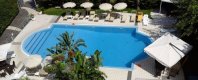 Piscina con ombrelloni e tavoli vista dall'alto.