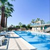Piscina con sedie bianche, palme e cielo blu.